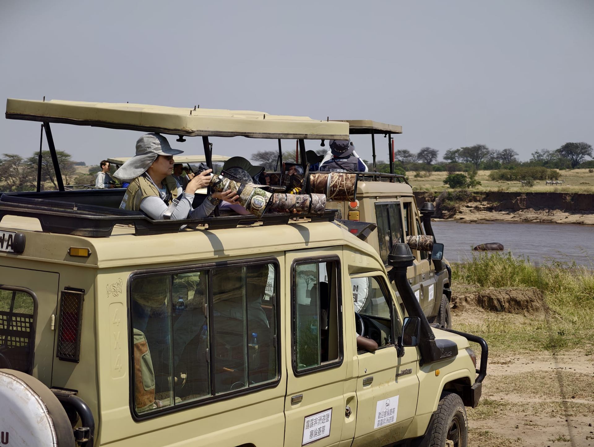 Guests photographing wildlife from a Lulu safari Land Cruiser